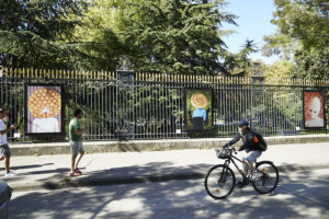 Dans la rue, des tableau sur les grilles d'un parc